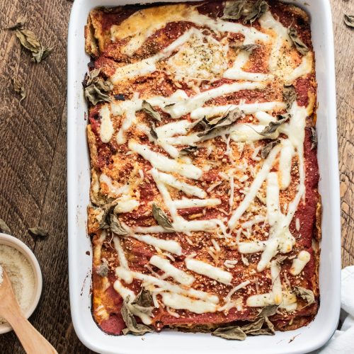 birds eye view of zucchini parmesan in a blue 9 x 13 inch baking dish on a wooden table