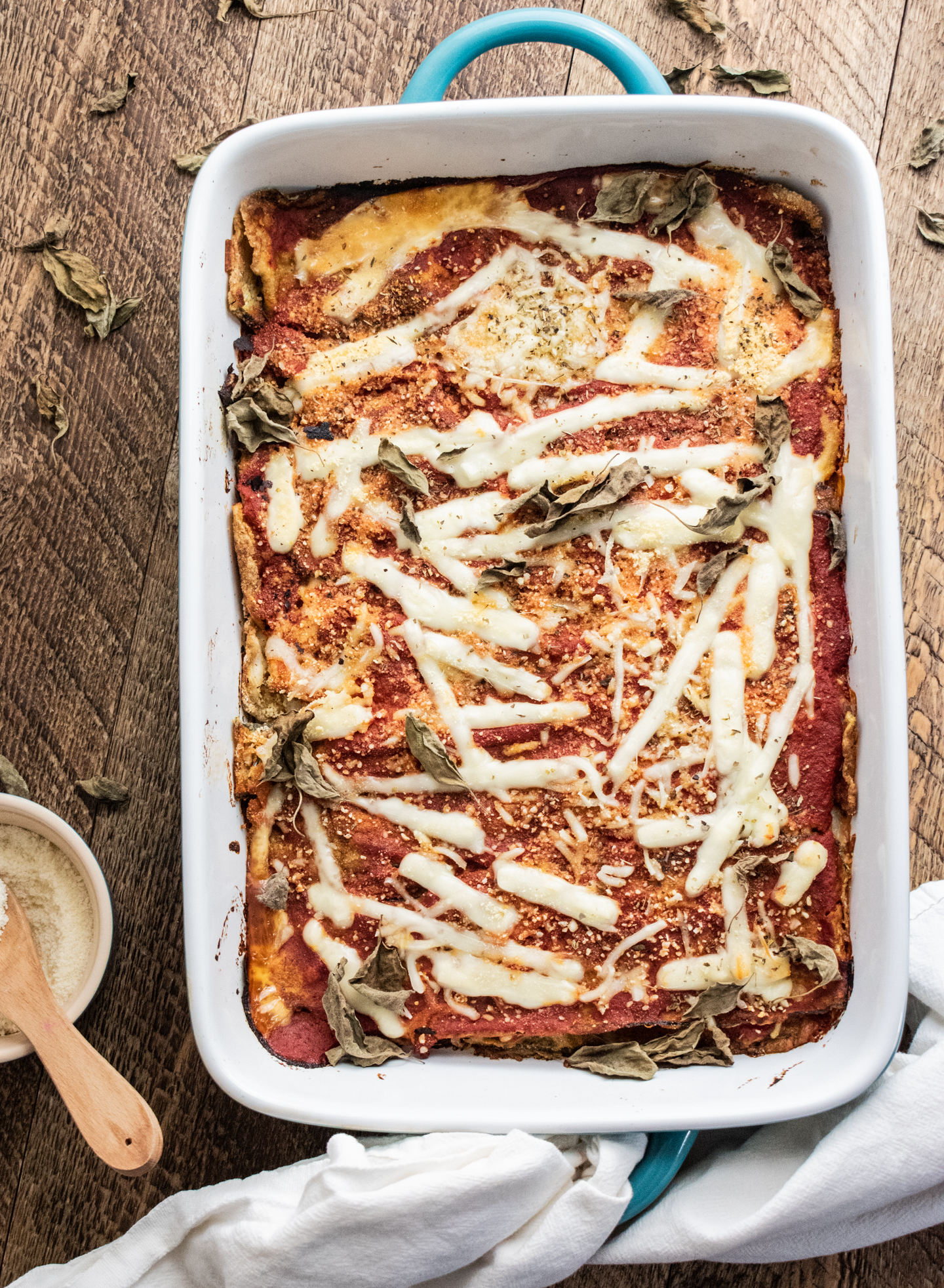 birds eye view of zucchini parmesan in a blue 9 x 13 inch baking dish on a wooden table