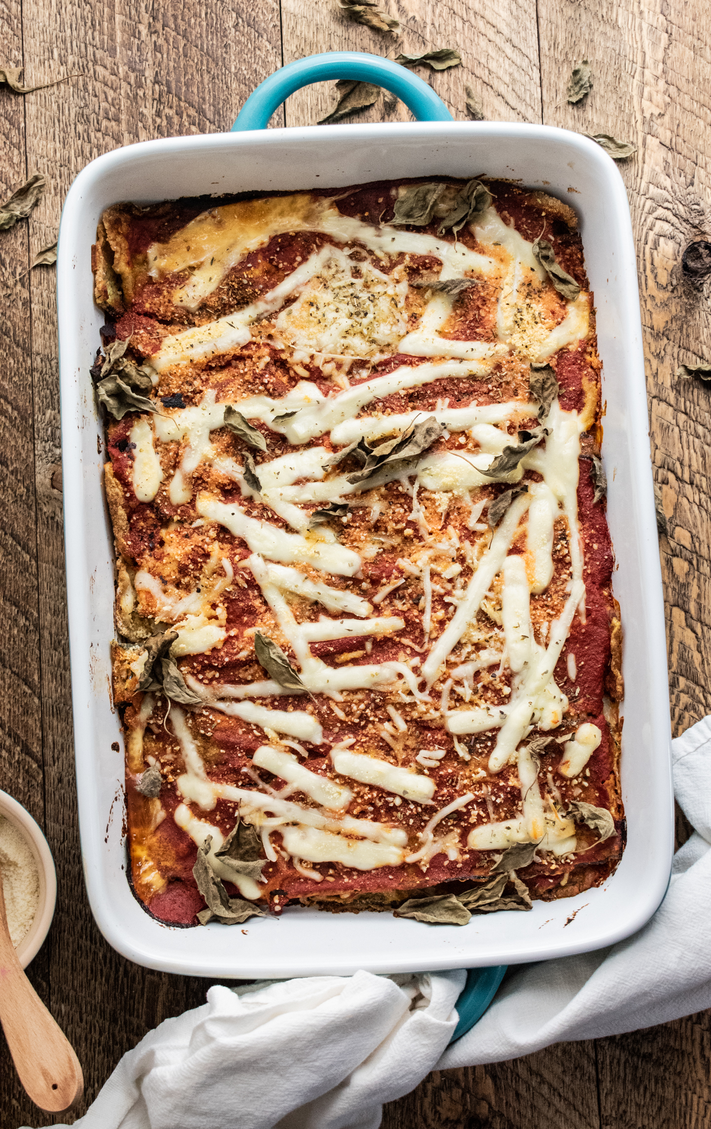 zucchini parmesan in a blue baking dish on a wooden table with a white napkin