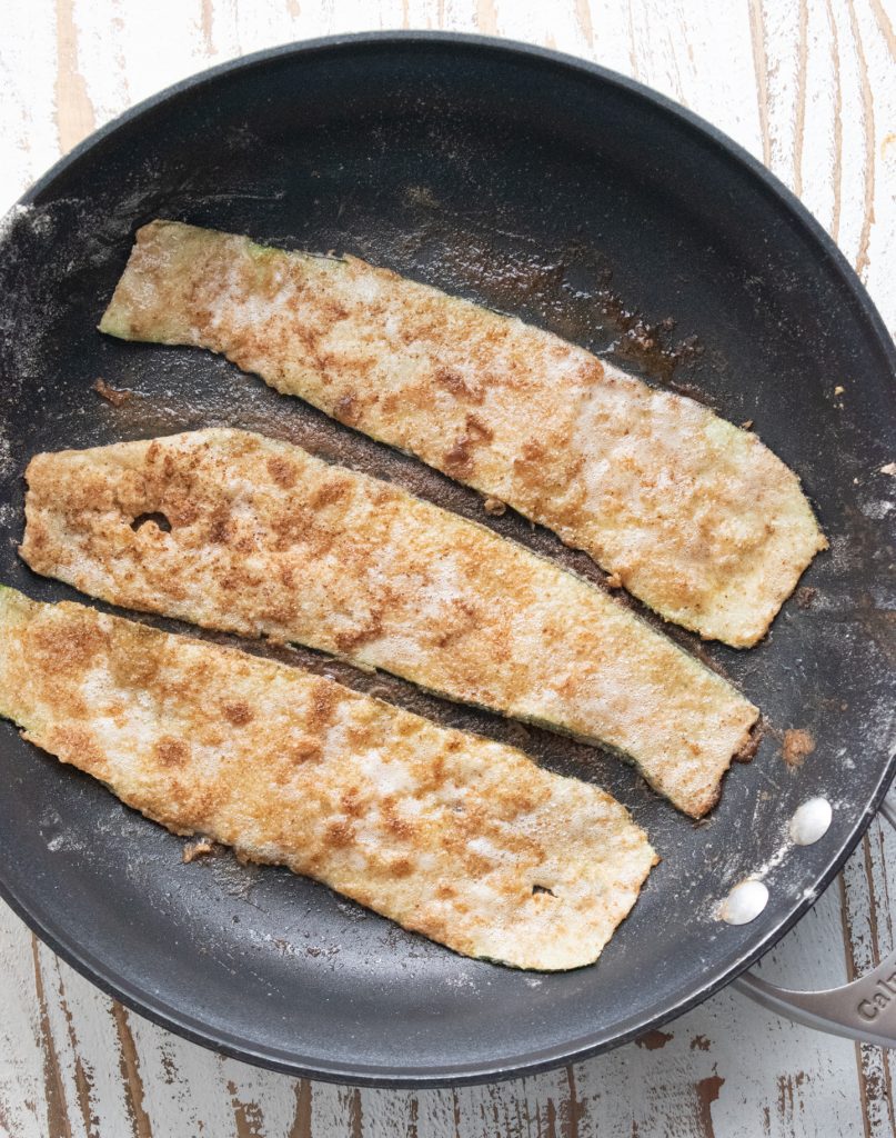 zucchini being pan fried on a frying pan