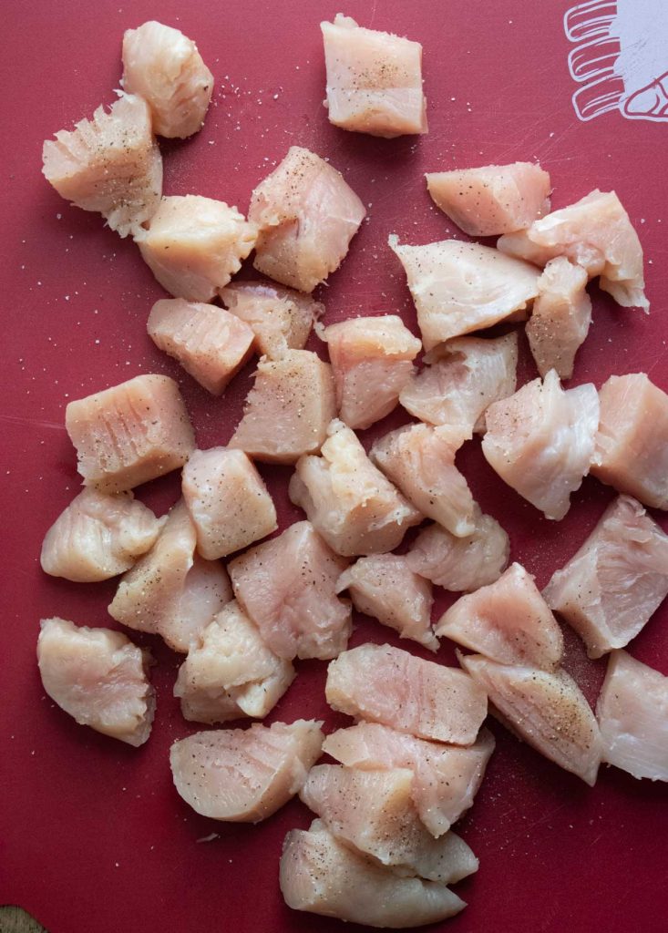 cubed chicken on a cutting board for making homemade baked chicken nuggets