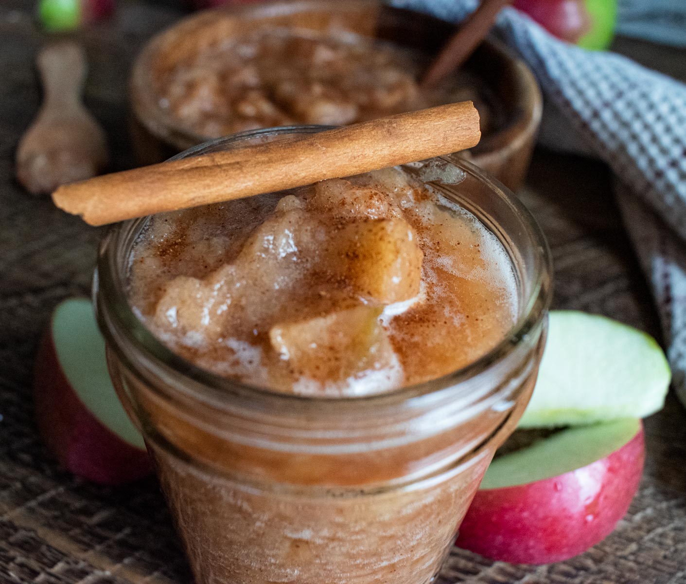 close up of homemade crockpot applesauce in a mason jar with a cinnamon stick on top