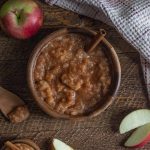 homemade crockpot applesauce in a wooden bowl on a wooden board