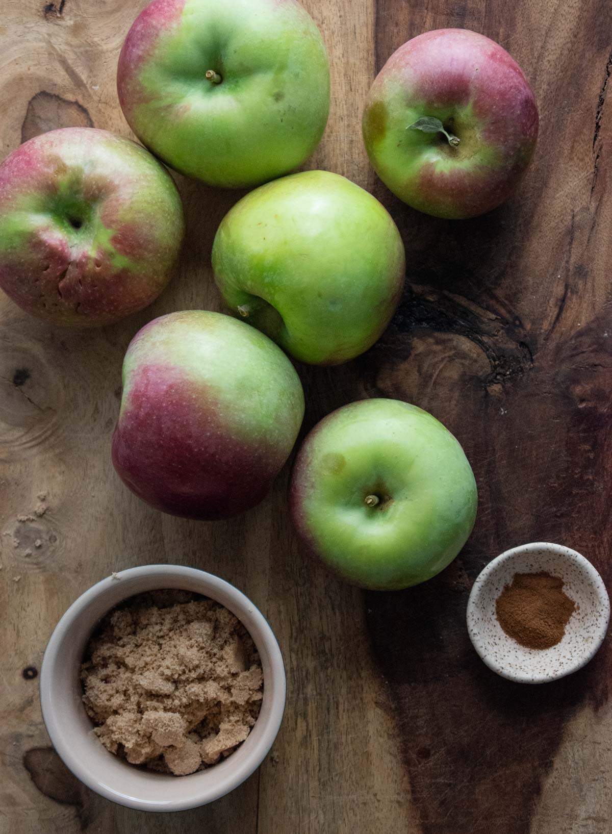 ingredients for homemade crockpot applesauce sitting on a wooden table