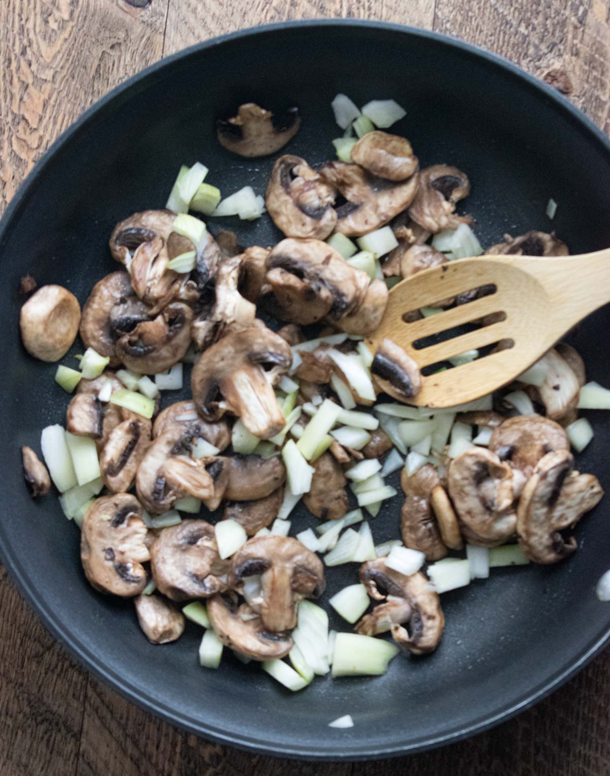 mushrooms and onions being cooked in a medium pan