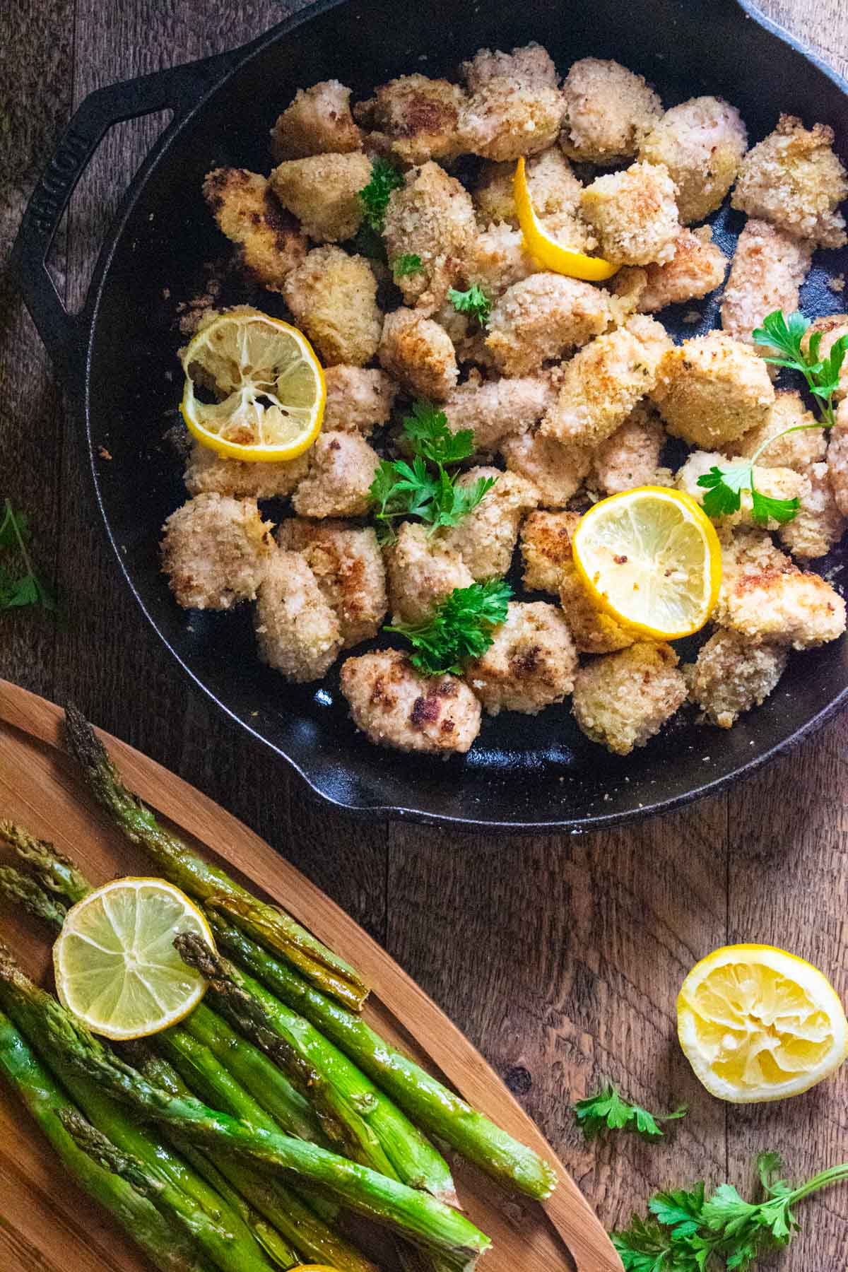 garlic butter chicken bites with lemon asparagus in a cast iron skillet on a wooden table