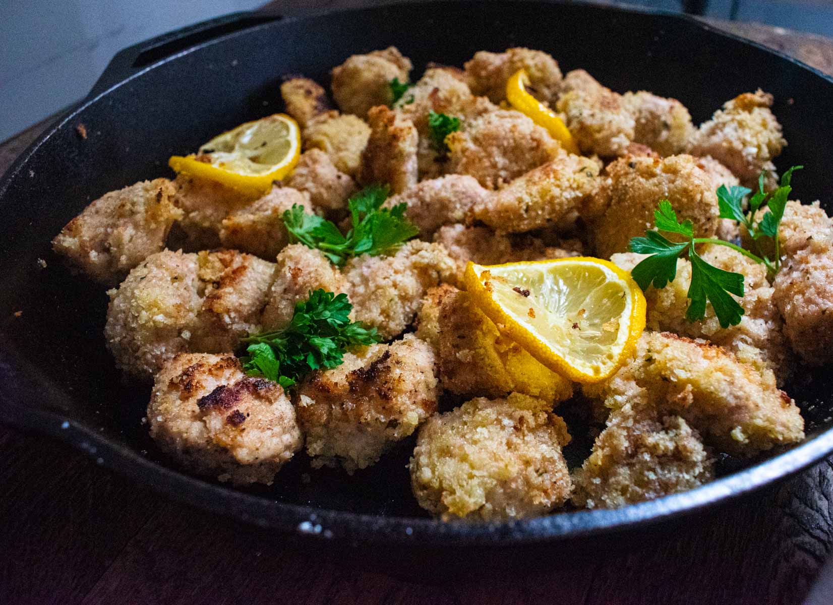 close up of garlic chicken bites with lemon slices and parsley on top