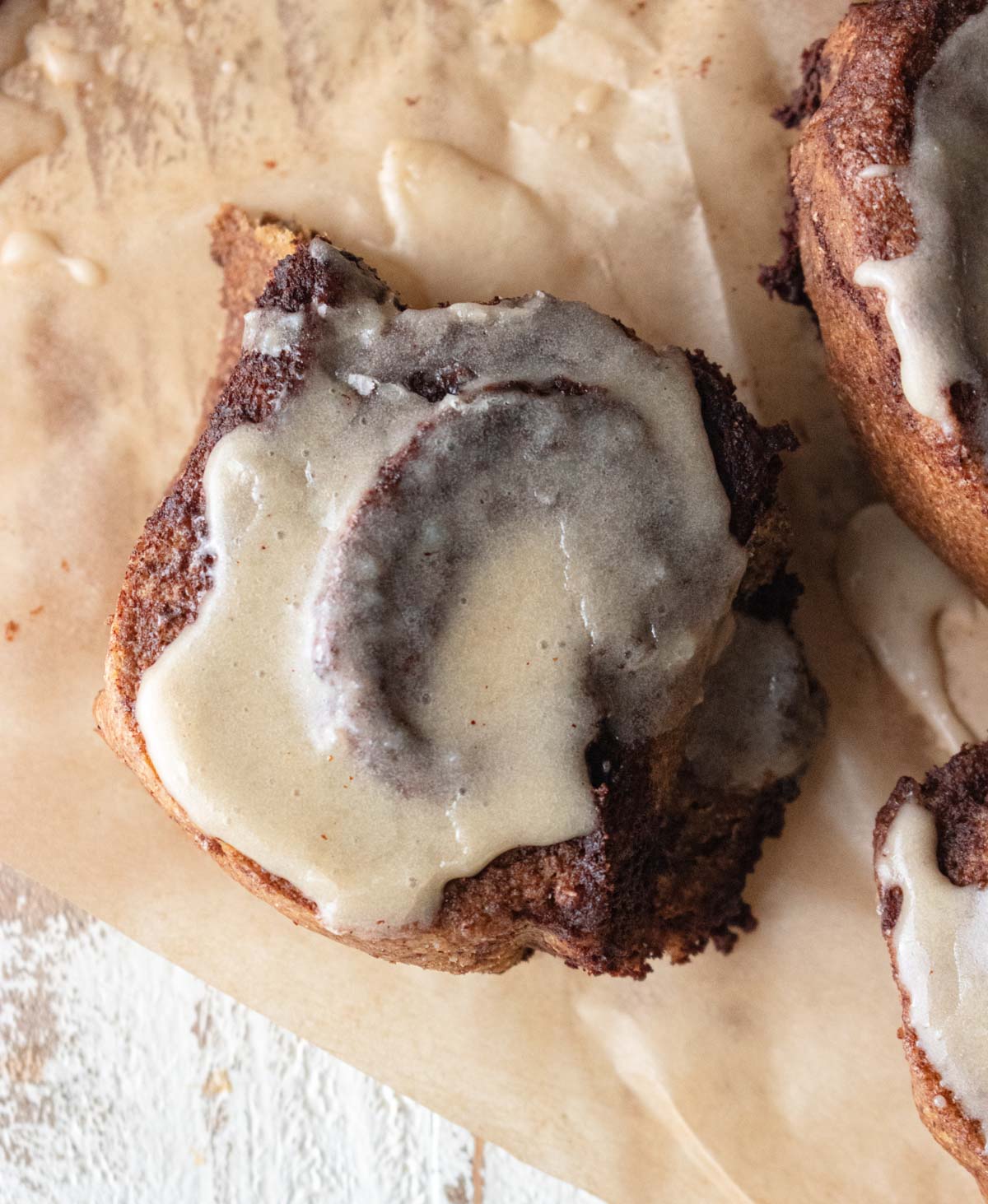 a close up of a delicious cinnamon roll with melted icing dripping down the sides. 