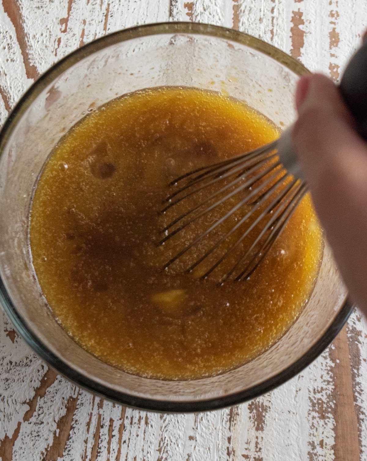 Step 1 when making these simple blondies. A birds eye view picture of butter, sugar, and eggs in a glass mixing bowl being whisked. 