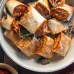 Close up of air fryer pizza rolls on a cream coloreed plate with a side of sace.