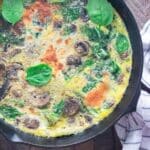 A birds-eye view of a veggie frittata in a Lodge cast-iron skillet on a wooden table.