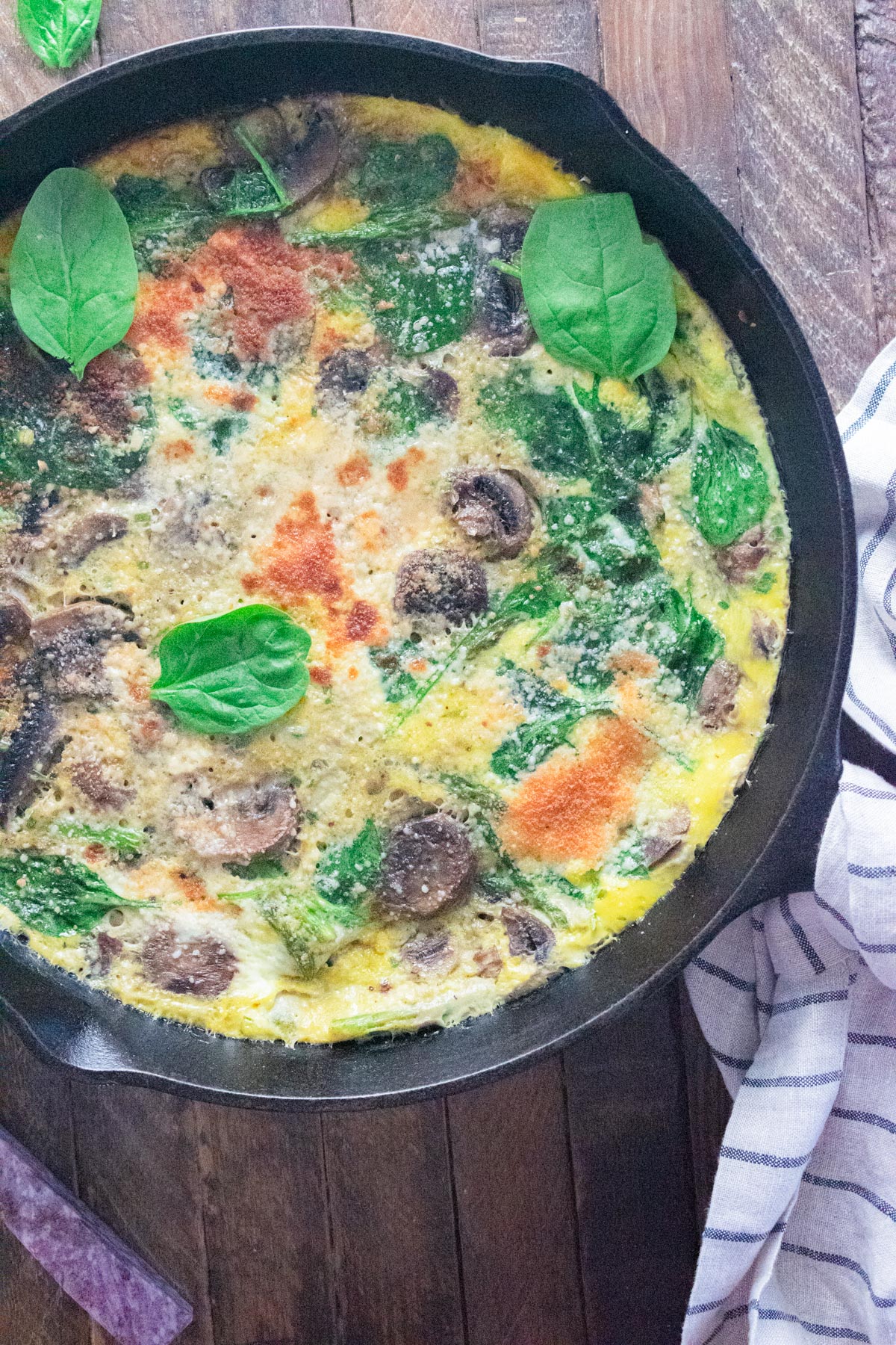 A close up of a veggie frittata in a Lodge cast-iron skillet on a wooden table.