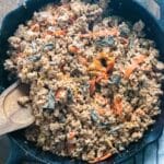Buffalo ground turkey in a Lodge skillet on a wooden table with a wooden spoon inserted in the side.