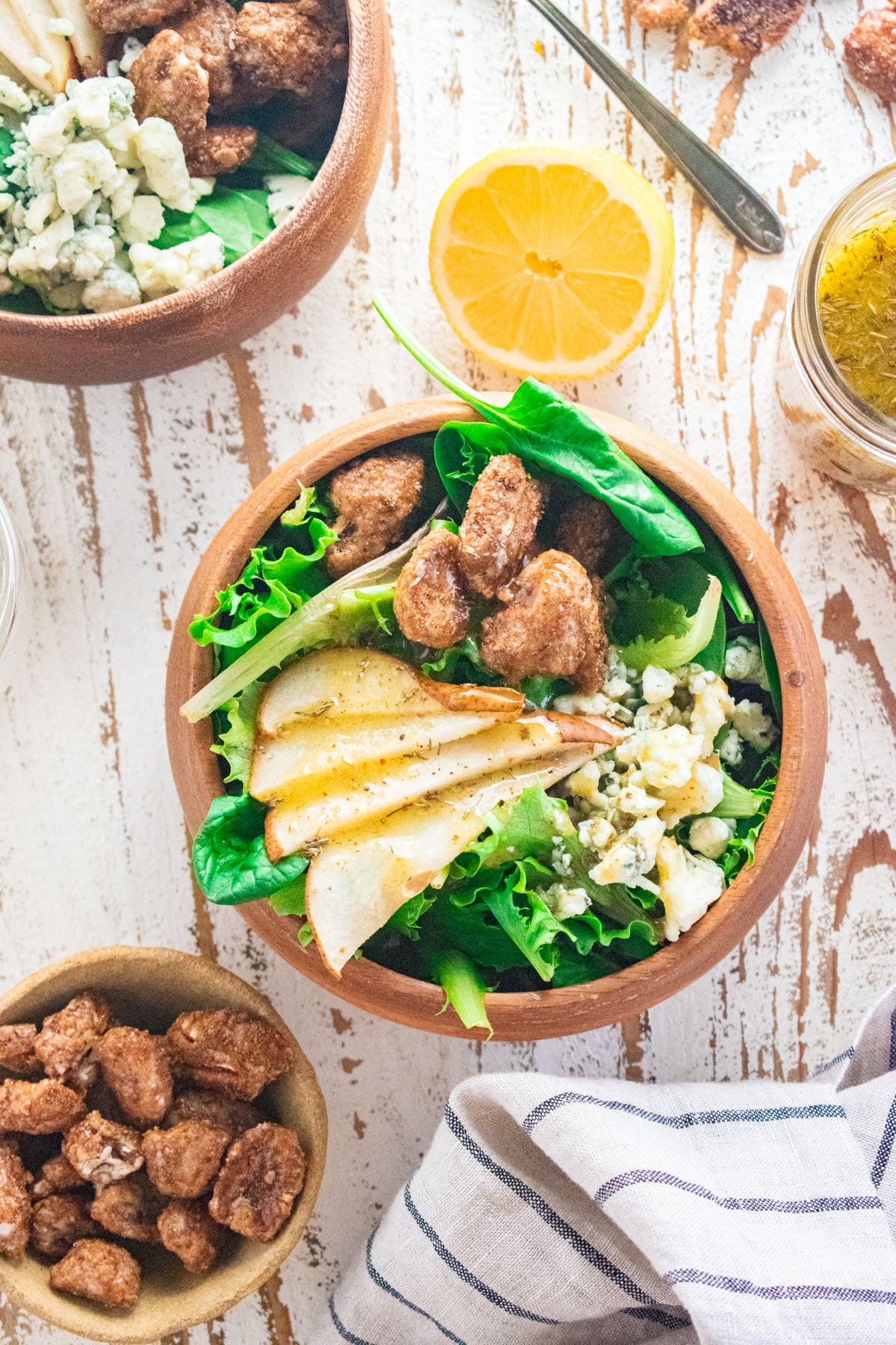 Birds eye view of a salad in a wooden bowl with sliced pears on top, gorgonzola cheese, and candied pecans.