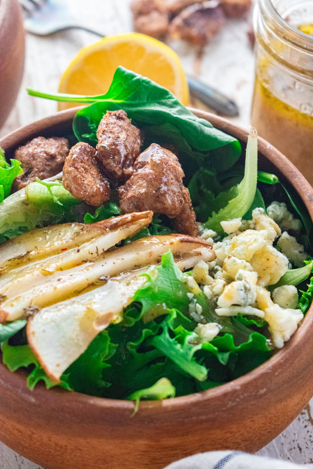 A close up of a baked pear and gorgonzola salad with salad dressing drizzled on top.