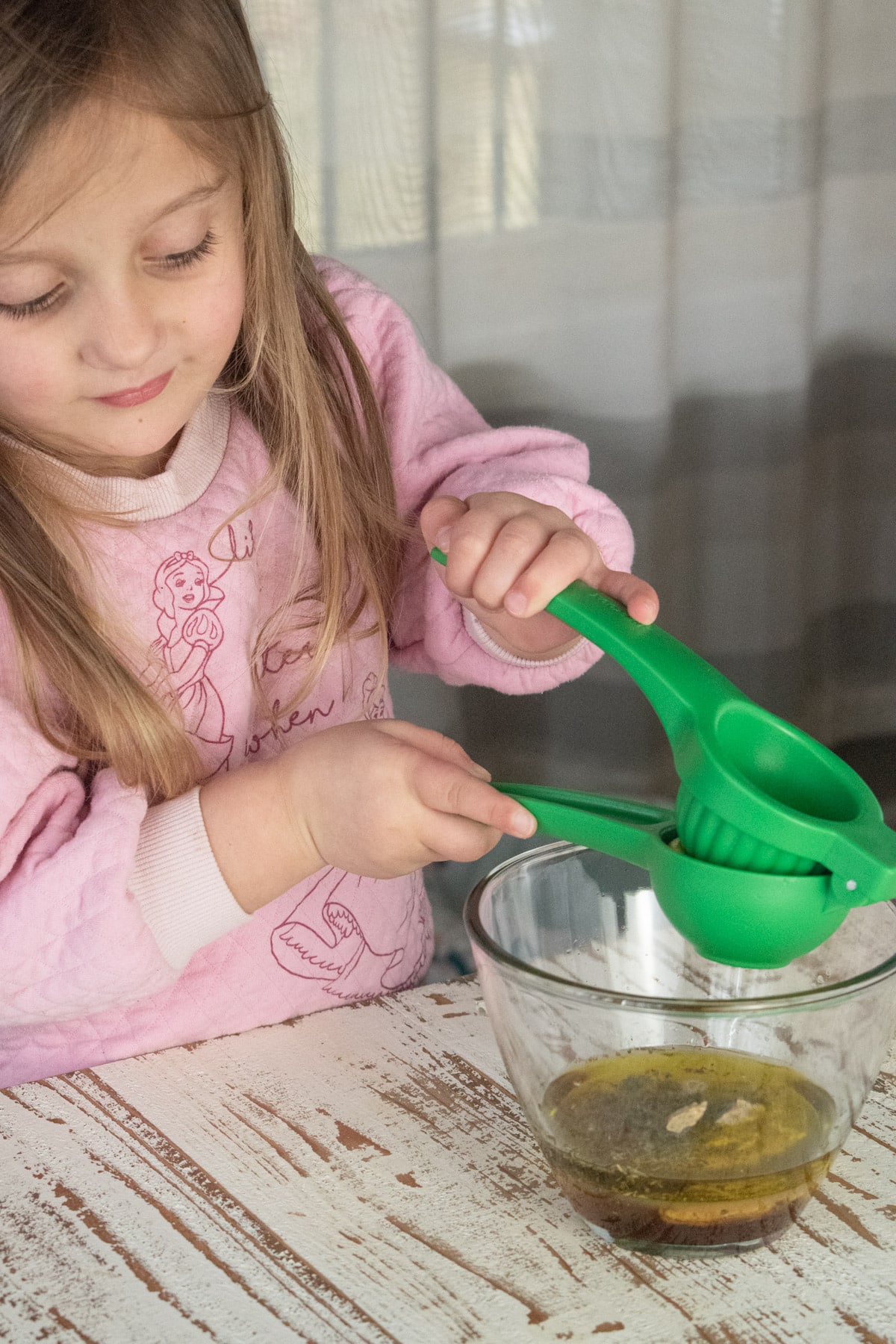 A little girl using a fruit squeezer to get juice out of a lemon.