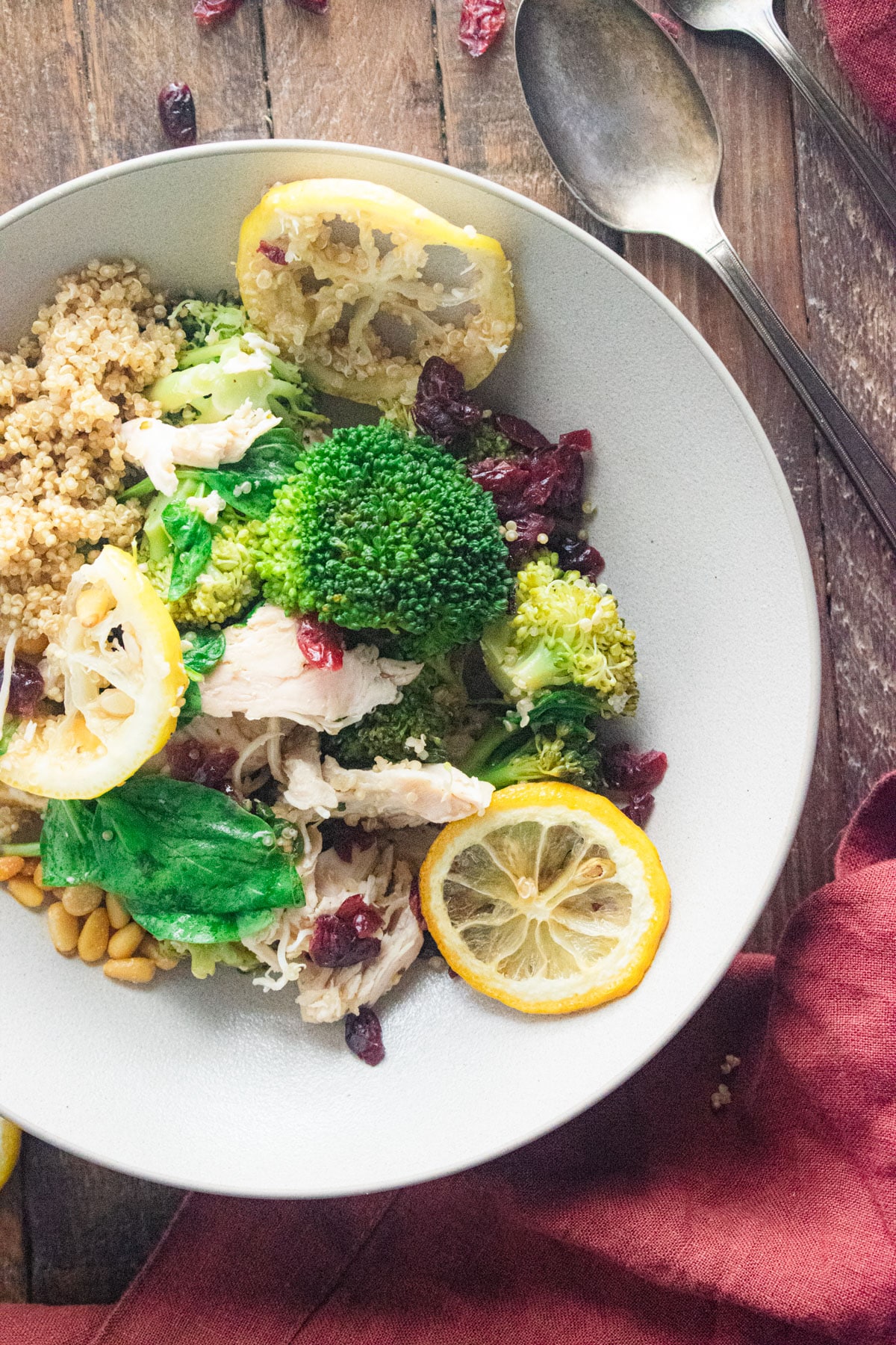 close up of juicy chicken quinoa bowl in a white bowl on a wooden table.