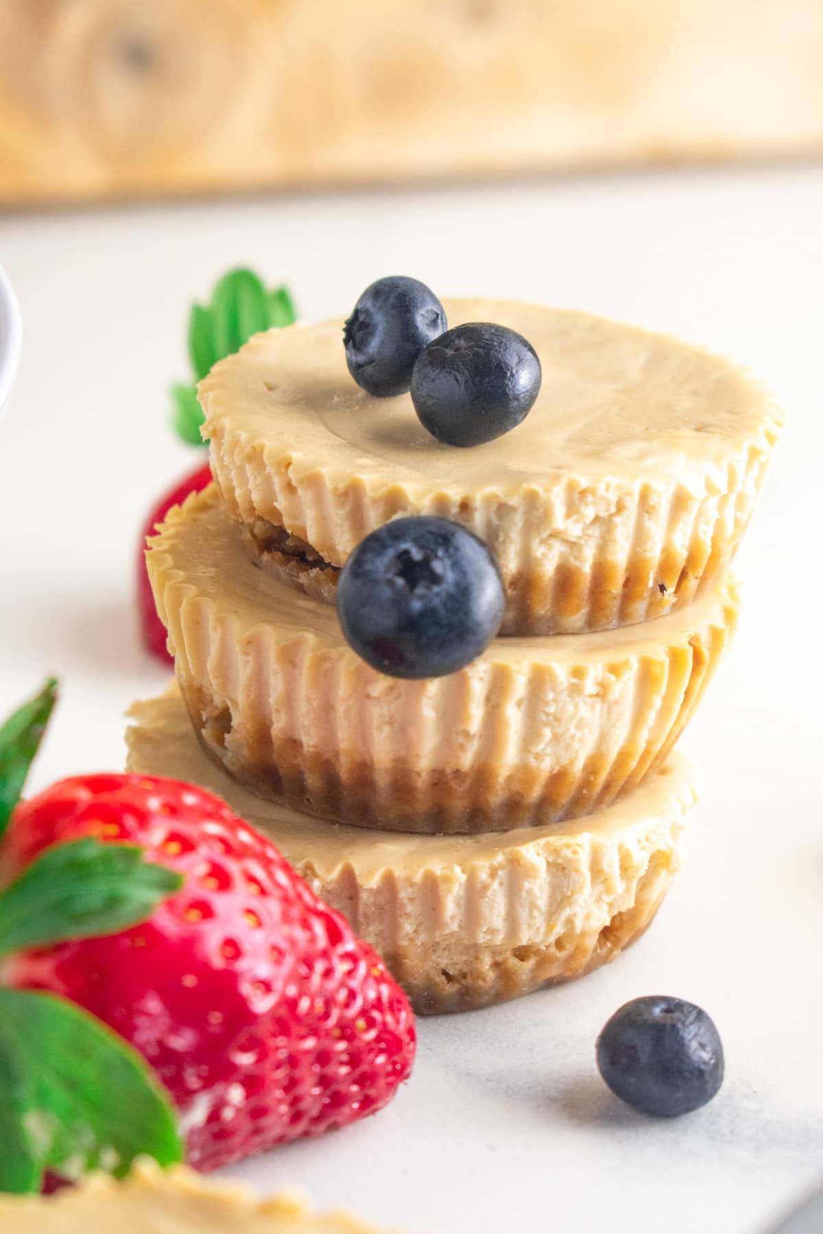 A close up of cheesecake muffins topped with blueberries and strawberries.